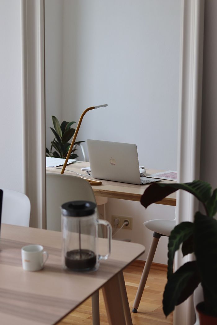 A cozy interior office with a laptop, desk lamp, and plants.