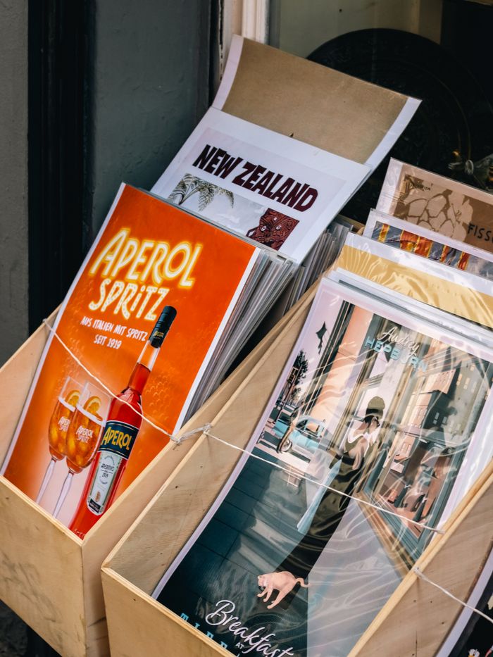 About Assorted vintage posters in a wooden stand featuring travel and beverage themes.