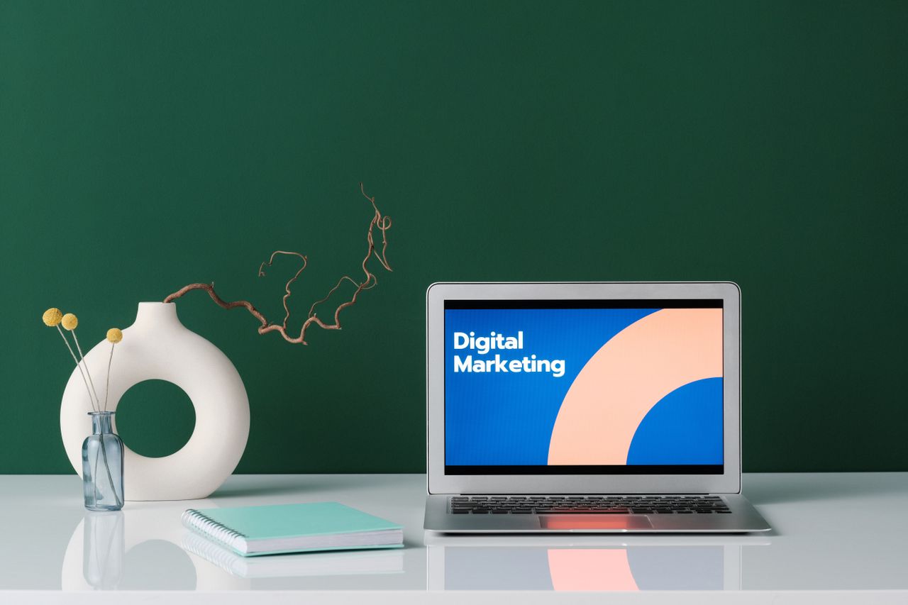 The Art of Drawing Readers In: Your attractive post title goes here A modern workspace featuring a laptop displaying 'Digital Marketing' against a green wall.